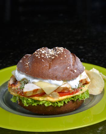 Sandwich de pollo y vegetales en pan de centeno con aderezo Cesar.